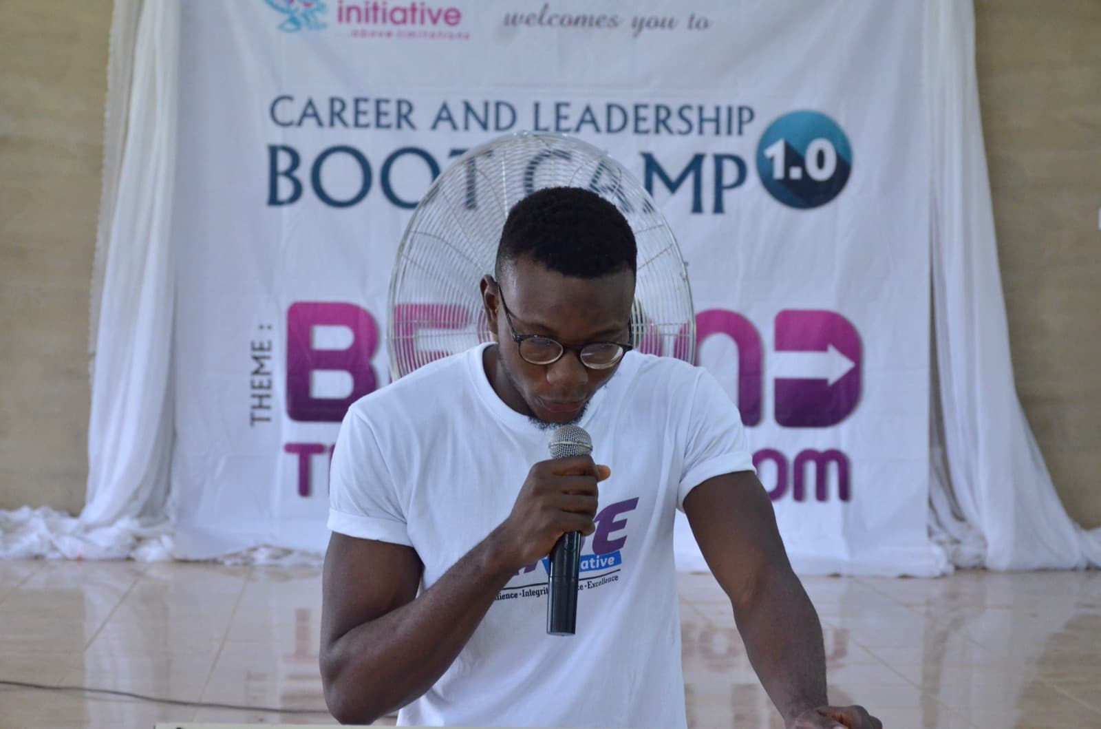 A facilitator with a microphone at the front of the hall, Best Legacy International Secondary School, 2019.