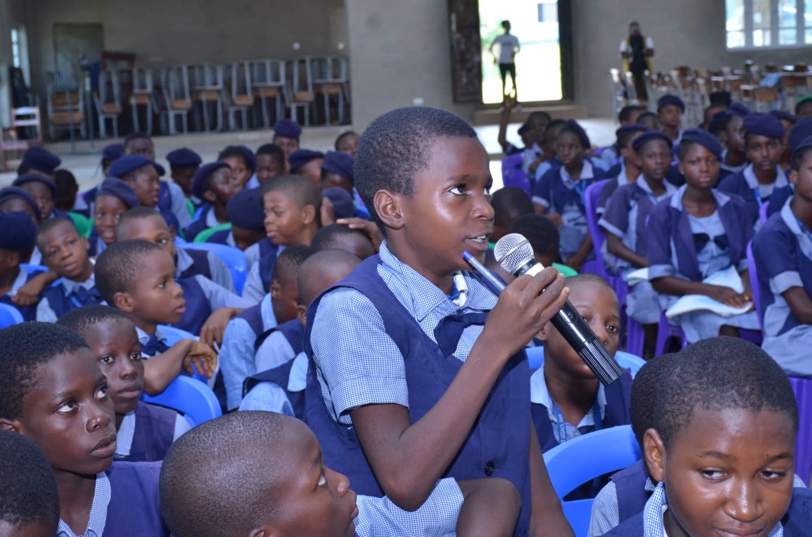 A student speaking into a microphone among their classmates at Best Legacy International Secondary School, 2019.