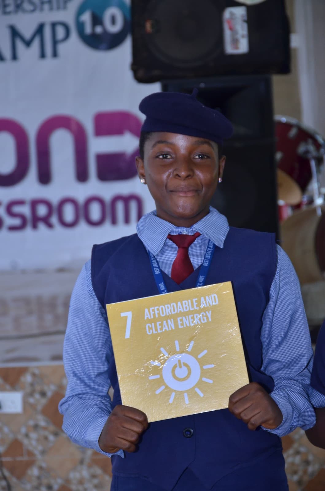 A student holding a Sustainable Development Goals card and smiling, Best Legacy International Secondary School, 2019.